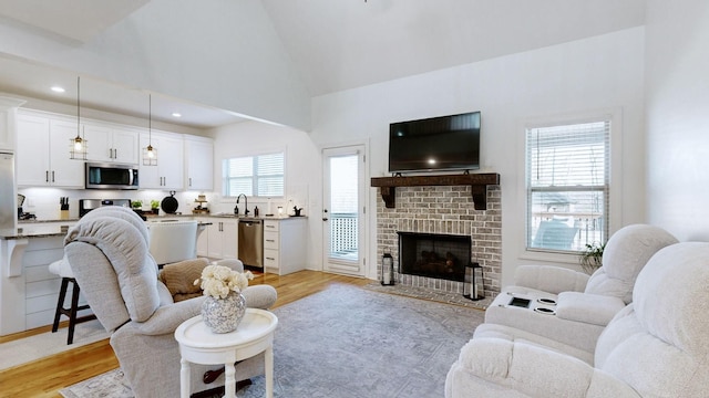 5020 E Mayflower Ct, Greenbrier, TN 37073 - living room featuring lofted ceiling, a brick fireplace, recessed lighting, and light wood-type flooring
