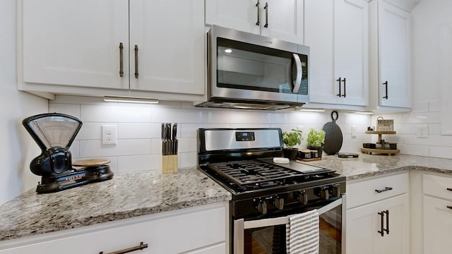 5020 E Mayflower Ct, Greenbrier, TN 37073 - kitchen featuring light stone counters, decorative backsplash, appliances with stainless steel finishes, and white cabinetry