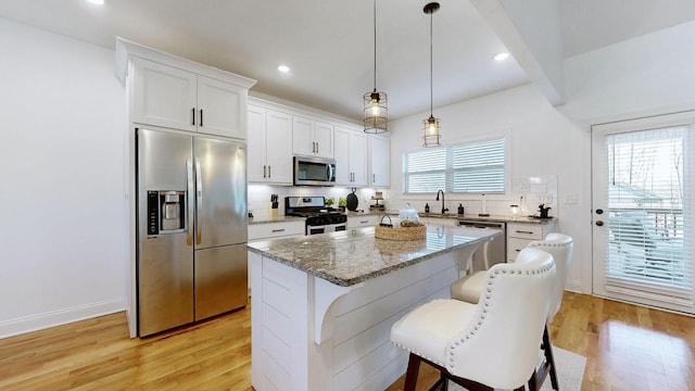 5020 E Mayflower Ct, Greenbrier, TN 37073 - kitchen with light wood-style flooring, a center island, stainless steel appliances, a breakfast bar area, and decorative backsplash