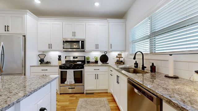 5020 E Mayflower Ct, Greenbrier, TN 37073 - kitchen featuring a sink, white cabinets, light wood-style floors, appliances with stainless steel finishes, and backsplash