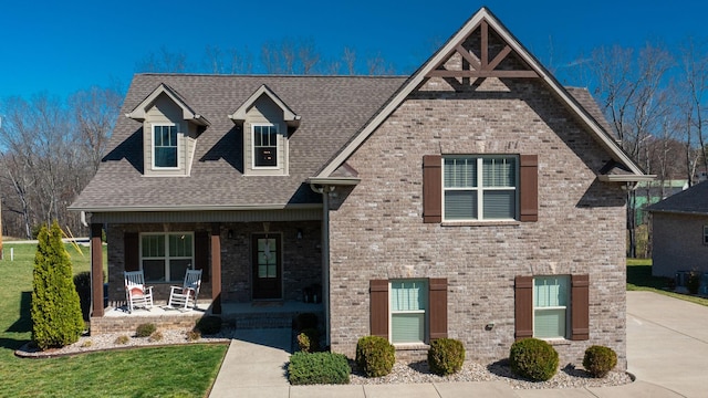 5020 E Mayflower Ct, Greenbrier, TN 37073 - view of front of house featuring roof with shingles, covered porch, a front yard, brick siding, and central AC unit