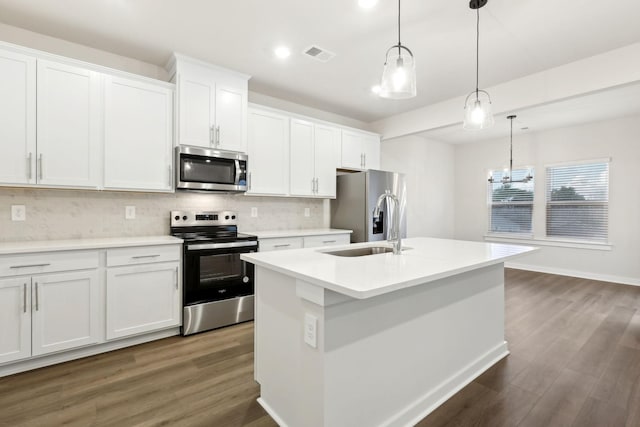 4228 Skyridge Dr, Nashville, TN 37207 - kitchen featuring appliances with stainless steel finishes, tasteful backsplash, dark wood-style floors, a center island with sink, and white cabinetry