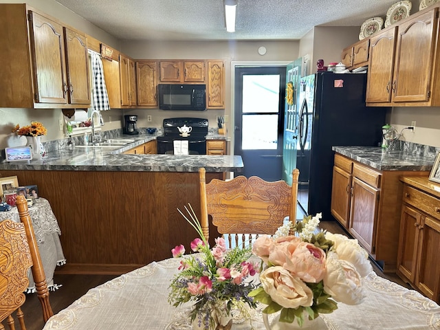 1306 Mcmahan St, Manchester, TN 37355 - kitchen with black appliances, a sink, a peninsula, brown cabinetry, and a textured ceiling
