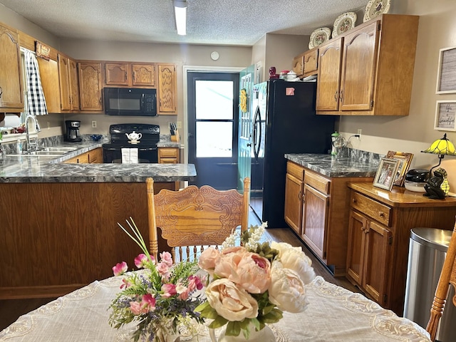 1306 Mcmahan St, Manchester, TN 37355 - kitchen featuring black appliances, a sink, a peninsula, brown cabinetry, and a textured ceiling