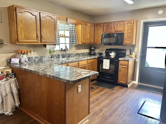 1306 Mcmahan St, Manchester, TN 37355 - kitchen featuring black appliances, a sink, a peninsula, dark wood-type flooring, and brown cabinetry