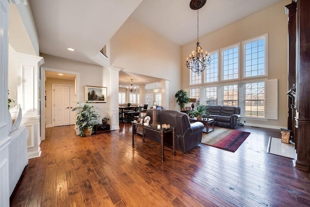 908 Plantation Blvd, Gallatin, TN 37066 - living area featuring dark wood-type flooring, a notable chandelier, decorative columns, baseboards, and a towering ceiling