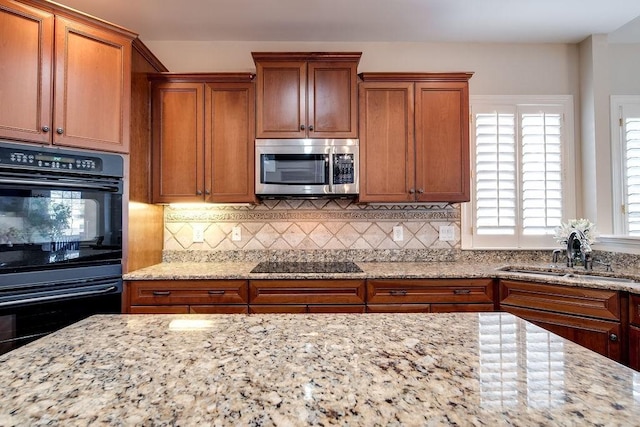 908 Plantation Blvd, Gallatin, TN 37066 - kitchen featuring black appliances, a sink, light stone counters, backsplash, and brown cabinetry