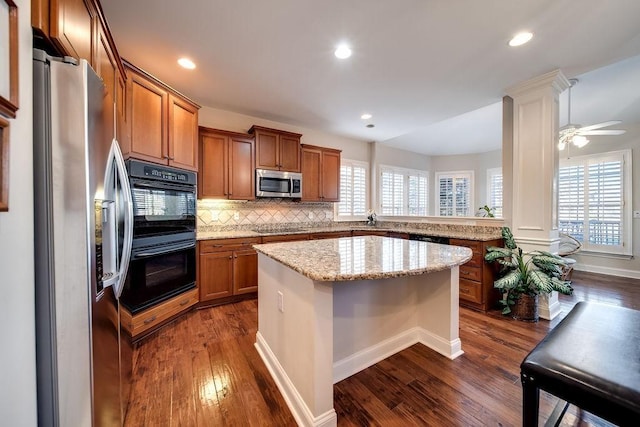 908 Plantation Blvd, Gallatin, TN 37066 - kitchen featuring brown cabinets, dark wood-type flooring, black appliances, a kitchen island, and decorative backsplash