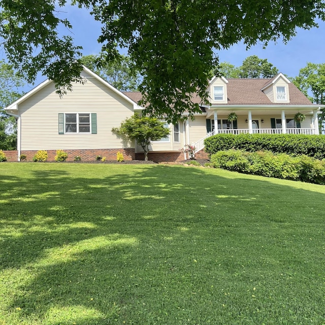 cape cod house with roof with shingles, covered porch, and a front lawn