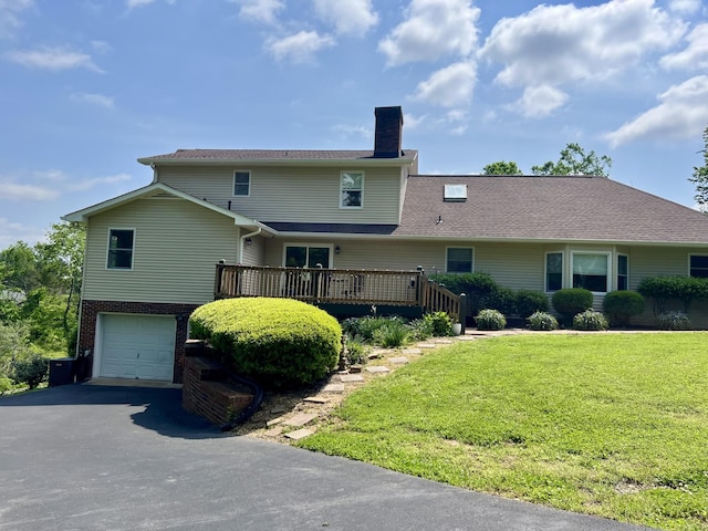 view of front of home with an attached garage, a wooden deck, a front yard, a chimney, and driveway