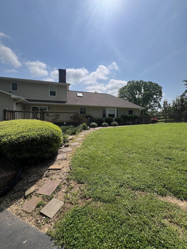 view of front of home with a wooden deck, a front yard, and a chimney