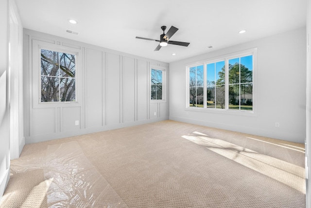 empty room featuring visible vents, light carpet, a ceiling fan, recessed lighting, and a decorative wall