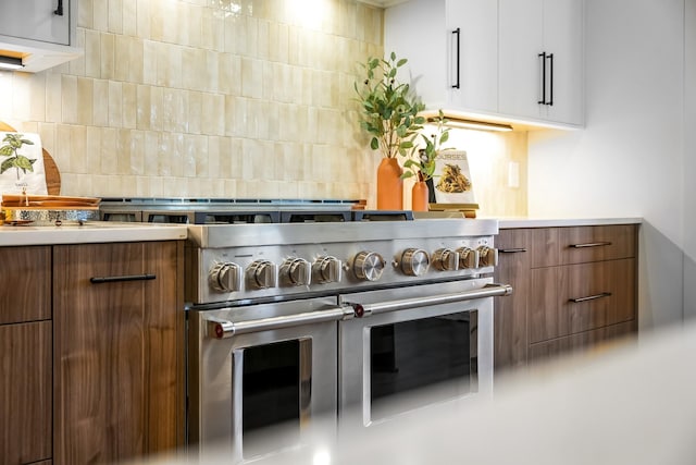 kitchen with decorative backsplash, light countertops, range with two ovens, and brown cabinets