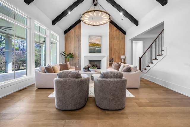 living area with an inviting chandelier, beamed ceiling, wood finished floors, and high vaulted ceiling