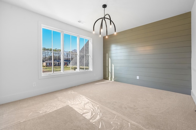 empty room with visible vents, carpet flooring, and wooden walls