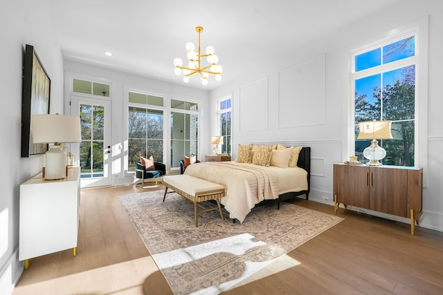 bedroom featuring a notable chandelier, recessed lighting, a decorative wall, and wood finished floors
