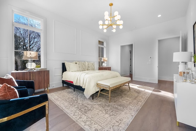 bedroom featuring recessed lighting, baseboards, an inviting chandelier, and wood finished floors