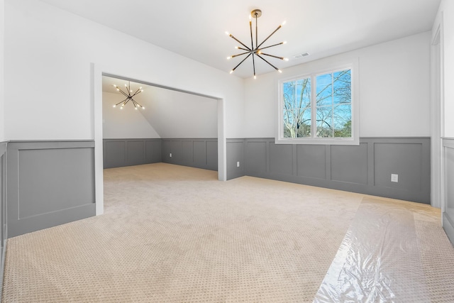 bonus room featuring visible vents, carpet, a chandelier, wainscoting, and a decorative wall