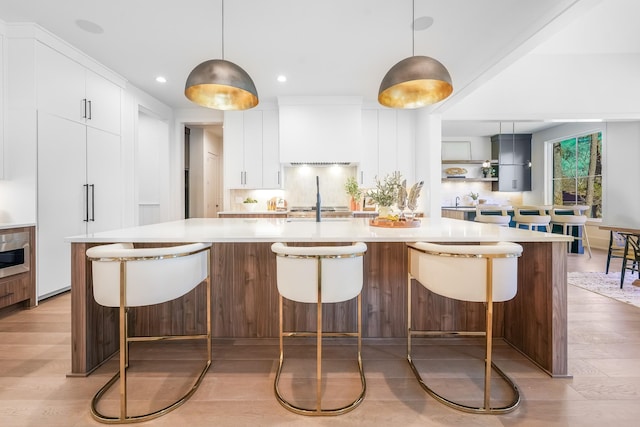 kitchen featuring modern cabinets, tasteful backsplash, light wood-style floors, white cabinets, and light countertops