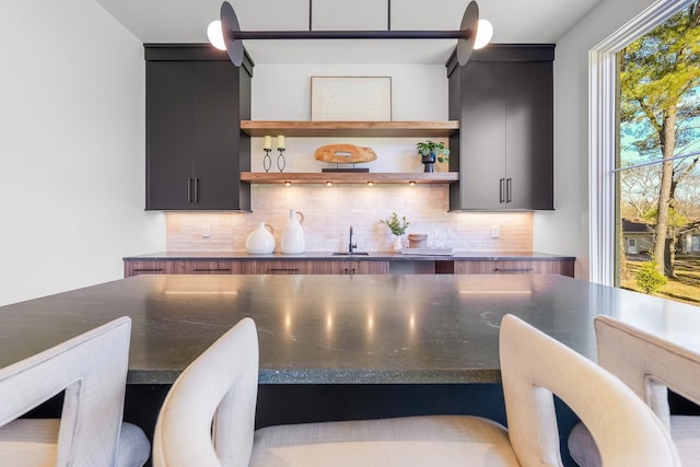 kitchen featuring decorative backsplash, open shelves, and dark cabinets