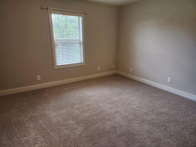 unfurnished room featuring carpet and baseboards