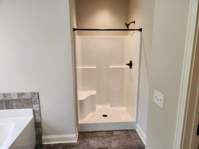 full bathroom featuring a garden tub, a shower, and baseboards
