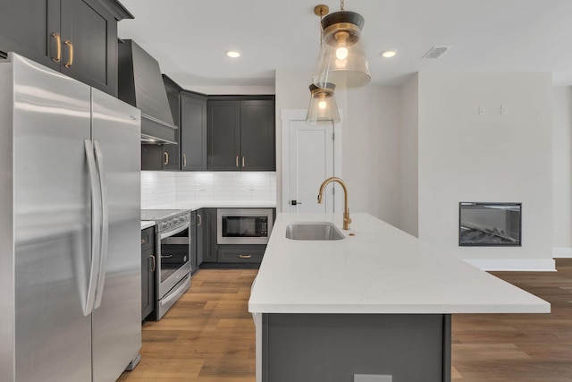 1016 W Kirkland Ave Unit C, Nashville, TN 37216 - kitchen featuring a kitchen island with sink, a sink, wood finished floors, stainless steel appliances, and wall chimney exhaust hood