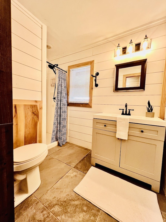full bath with tile patterned flooring, vanity, toilet, a shower with shower curtain, and wooden walls