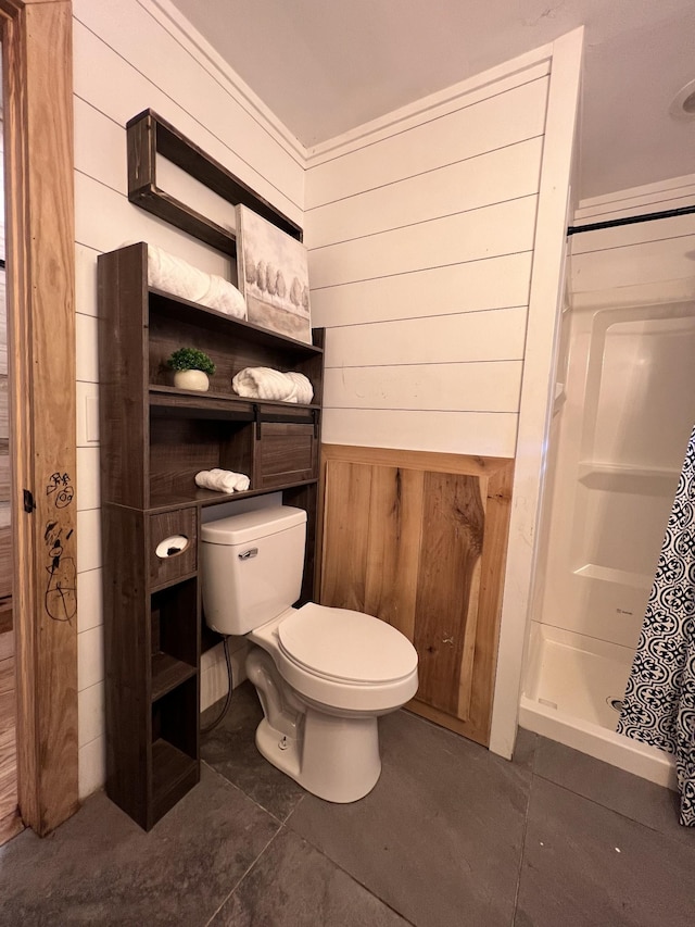 bathroom with wooden walls, tile patterned flooring, a stall shower, and toilet