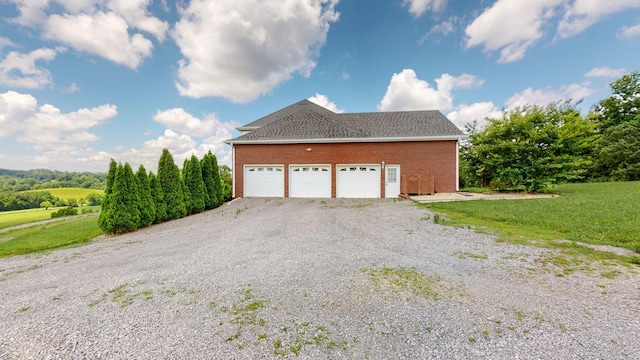 view of home's exterior featuring brick siding, a lawn, an attached garage, and gravel driveway