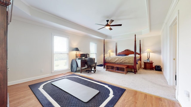 bedroom with baseboards, crown molding, a tray ceiling, and wood finished floors