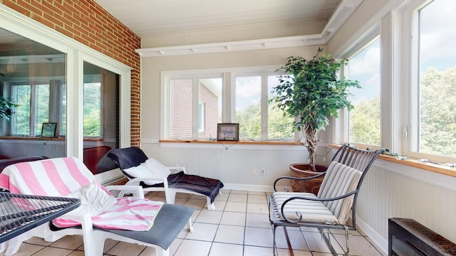 sunroom featuring tile patterned flooring and brick wall