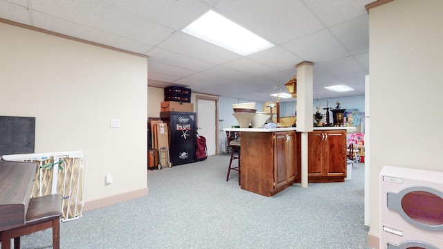 kitchen featuring baseboards, carpet, a drop ceiling, a breakfast bar area, and washer / clothes dryer