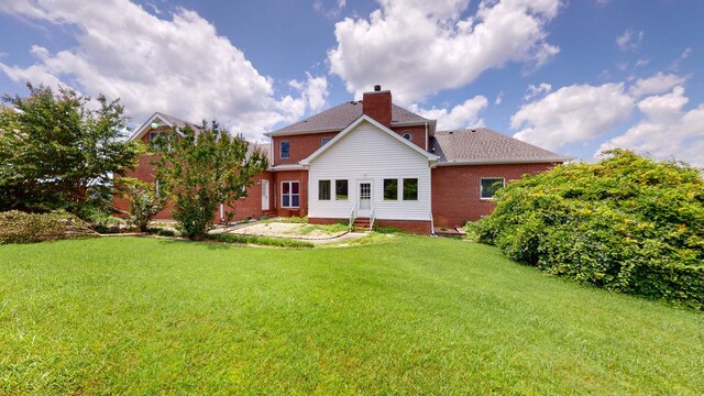 back of house with a lawn, entry steps, and a chimney
