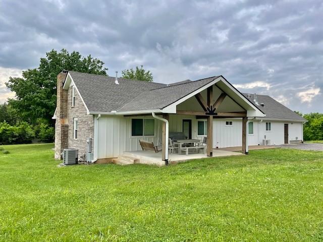 744 Dobbins Pike, Gallatin, TN 37066 - rear view of property with board and batten siding, central AC unit, a chimney, a lawn, and a patio area