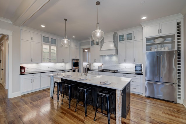 209 Gilchrist S Cir, Nolensville, TN 37135 - kitchen with appliances with stainless steel finishes, custom range hood, a sink, wood finished floors, and a kitchen bar