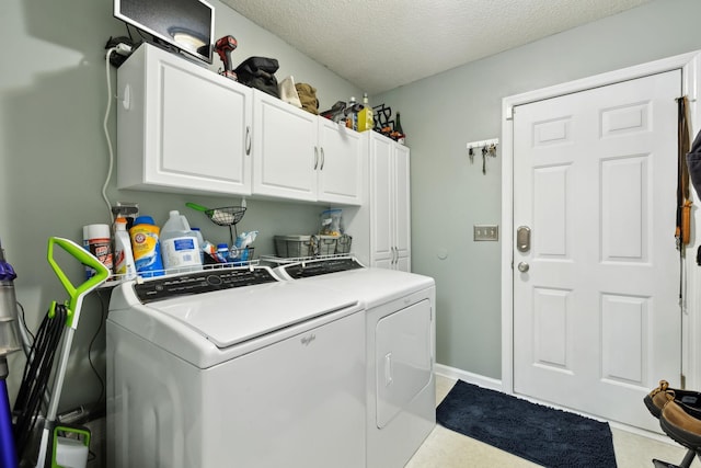laundry area with cabinet space, independent washer and dryer, a textured ceiling, and baseboards