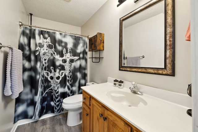 bathroom featuring toilet, vanity, a shower with curtain, wood finished floors, and a textured ceiling