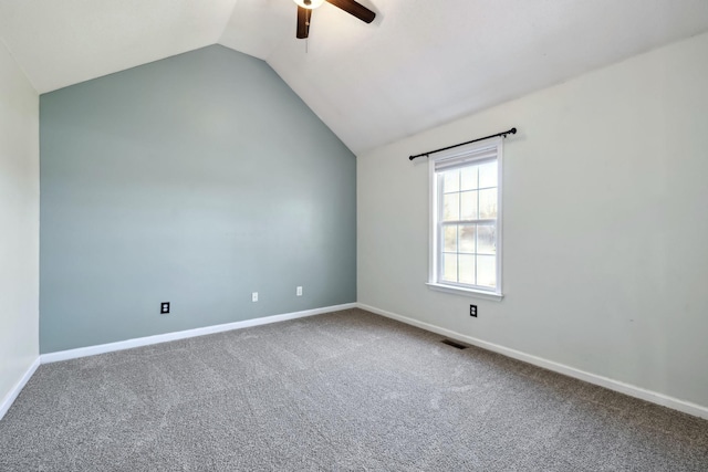 carpeted empty room featuring visible vents, baseboards, a ceiling fan, and vaulted ceiling
