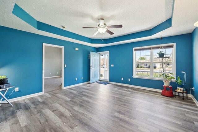 interior space featuring a ceiling fan, wood finished floors, baseboards, and a textured ceiling