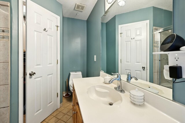 bathroom with visible vents, a stall shower, a textured ceiling, tile patterned flooring, and vanity