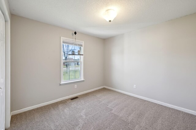 empty room with baseboards, carpet, visible vents, and a textured ceiling