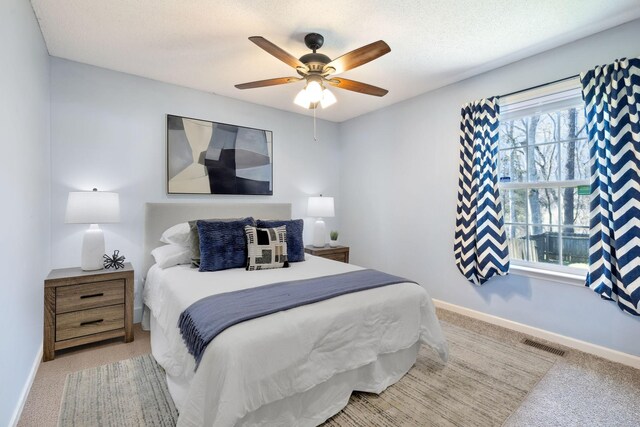 carpeted bedroom with a ceiling fan, baseboards, and visible vents