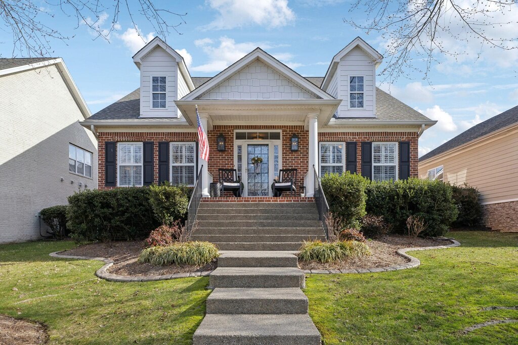 view of front of property with a front lawn, covered porch, and brick siding