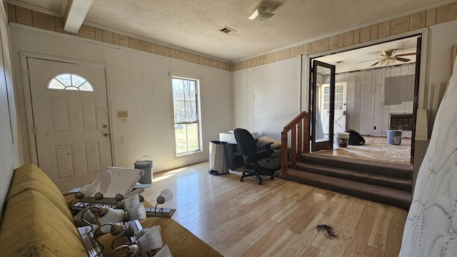 entryway featuring visible vents, ornamental molding, a textured ceiling, and wood finished floors