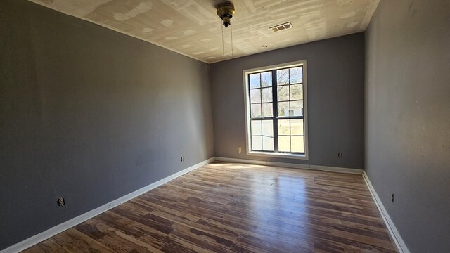 spare room with visible vents, baseboards, and dark wood-style flooring