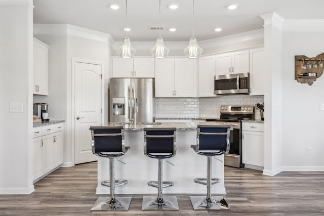 kitchen featuring wood finished floors, stainless steel appliances, white cabinets, crown molding, and decorative backsplash