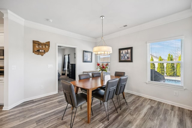 dining room featuring crown molding, wood finished floors, visible vents, and baseboards