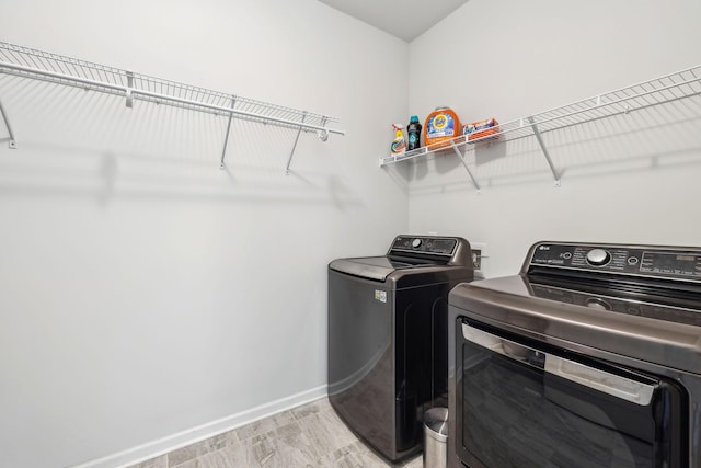 laundry room featuring laundry area, washer and dryer, light wood-style flooring, and baseboards