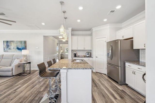 kitchen with visible vents, a sink, white cabinets, stainless steel refrigerator with ice dispenser, and open floor plan